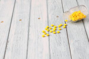 瓶から出て床に散らばる黄色の錠剤
